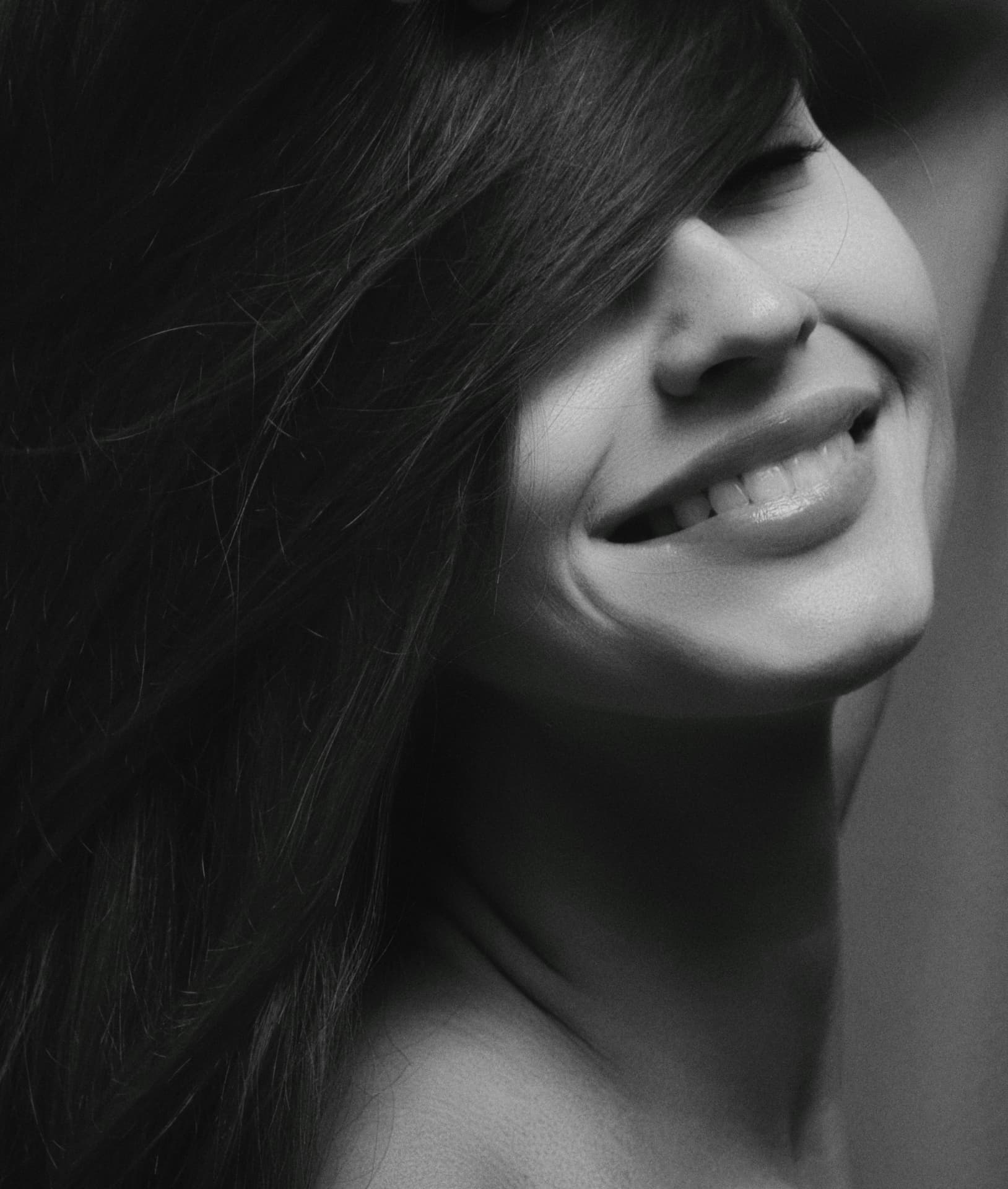 Black-and-white close-up of a woman's relaxed smile in profile