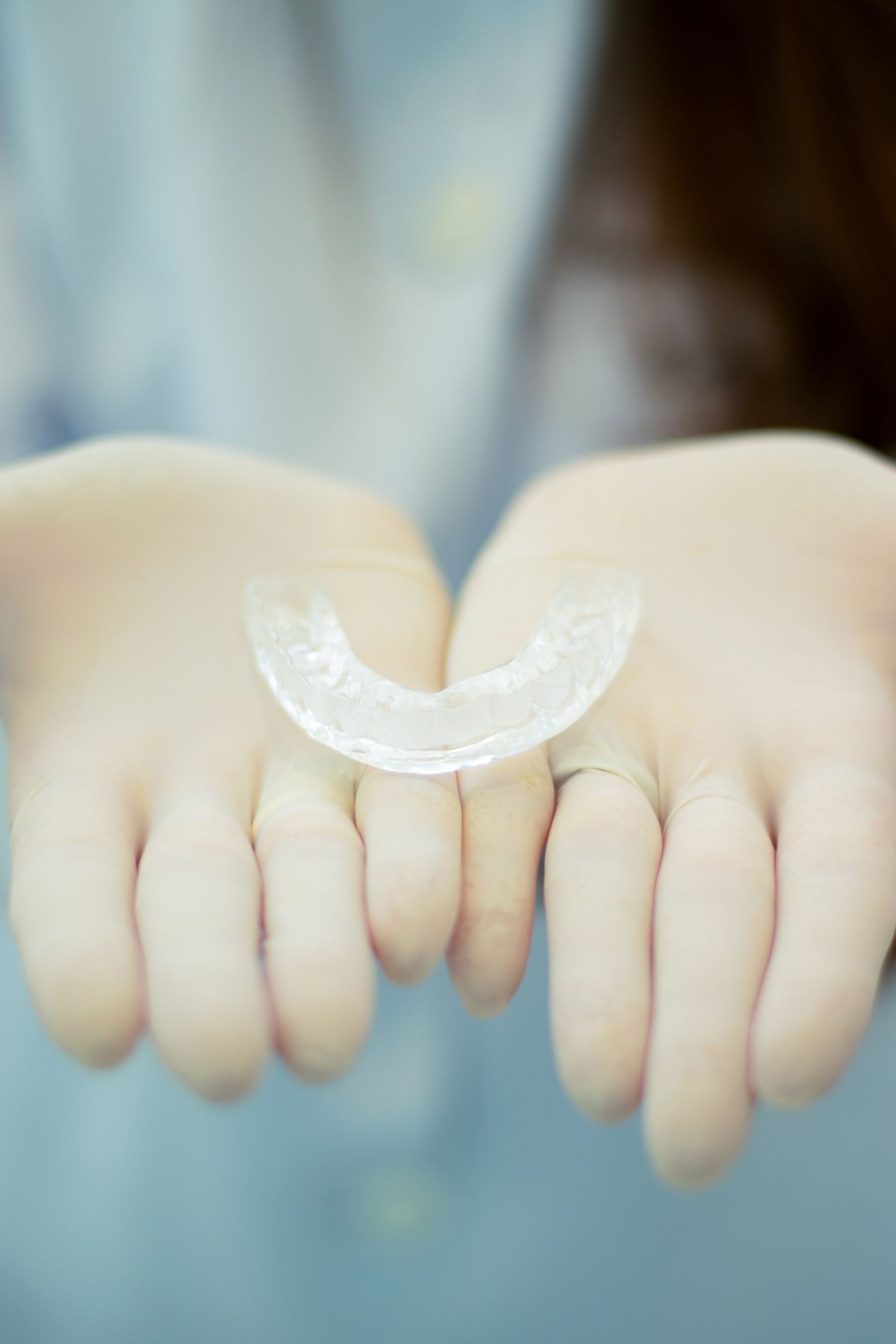 Clear custom-fit acrylic night guard held in gloved hands